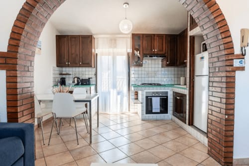 CefalHome Rome kitchen-dining area with dark wood cabinets, brick archway, and modern appliances