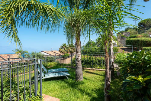 Sunny garden at CefalHome with palm trees, loungers, and sea views in Rome