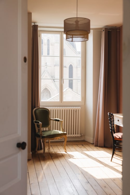 Chambre élégante à La Maison D'olivier avec vue sur château français, fauteuil ancien, parquet et lumière naturelle
