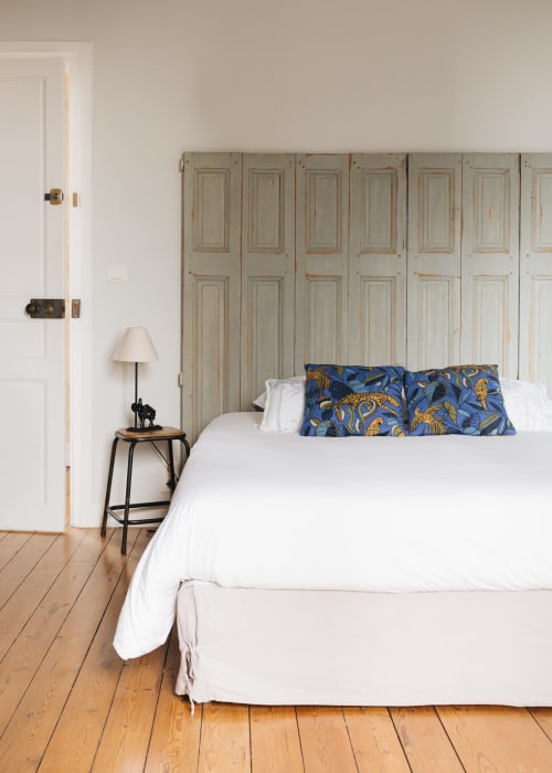 Chambre lumineuse à La Maison D'olivier avec lit blanc, oreillers à motifs bleus, parquet et armoire vintage à Mesnard
