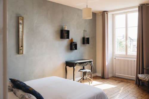 Chambre lumineuse à La Maison D'olivier B&B avec lit blanc, bureau noir, parquet et vue sur les monuments depuis les fenêtres
