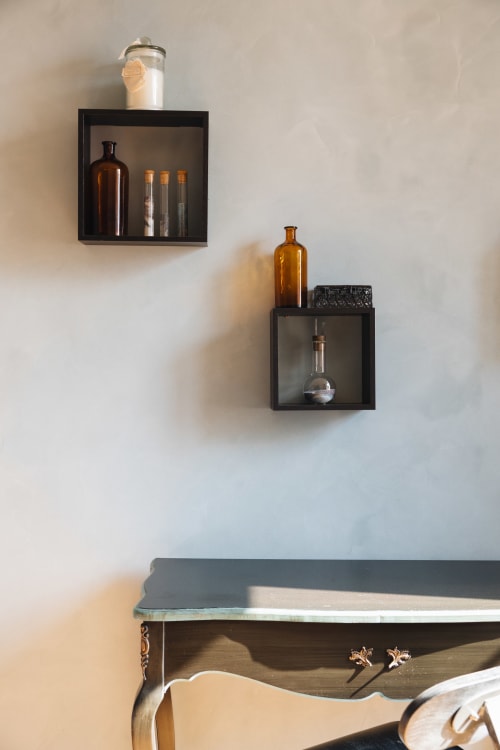 Étagères murales noires avec bouteilles en verre et objets de décoration dans la chambre de La Maison D'olivier B&B