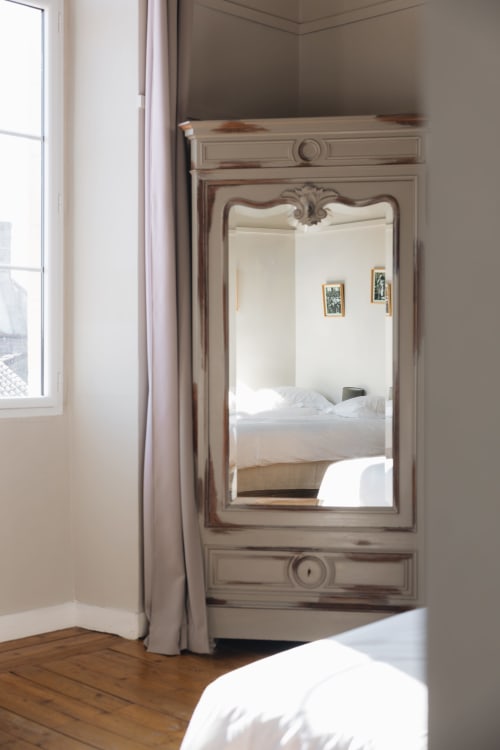 Miroir élégant à La Maison D'olivier B&B reflétant le lit aux draps blancs et la vue sur la fenêtre