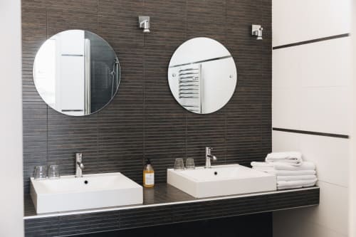 Salle de bains moderne à La Maison D'olivier avec doubles vasques, miroirs circulaires et dosseret en carrelage foncé à Mesnard La Barotière