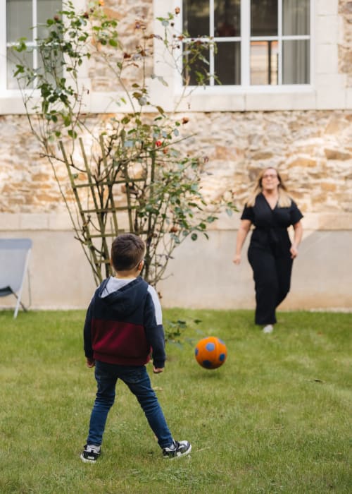 Enfant jouant au football avec un adulte dans le jardin-cour de La Maison D'olivier B&B, Mesnard La Barotière