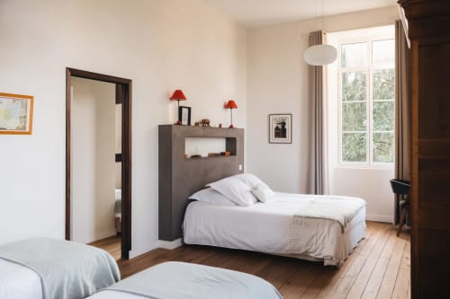 Chambre spacieuse à La Maison D'olivier BnB avec lits jumeaux, rangements modernes, lampes rouges et vue sur le jardin