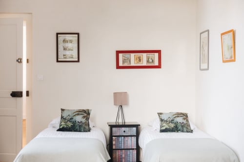 Chambre twin à La Maison D'olivier B&B avec lits blancs, oreillers botaniques, tableaux encadrés et table de nuit