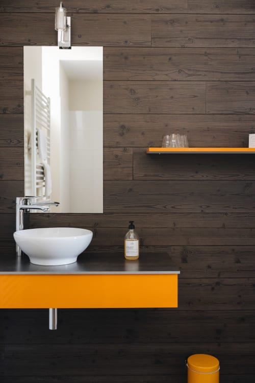 Vasque blanche moderne avec finitions orangées, murs en bois foncé à La Maison D'olivier