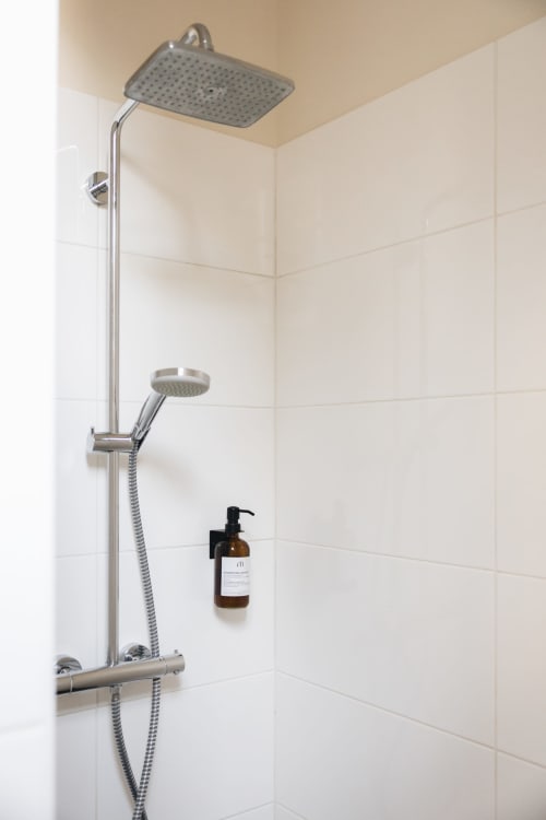 Salle de bain moderne à La Maison D'olivier avec douche à effet pluie, douchette à main, mitigeur thermostatique et savon ambré