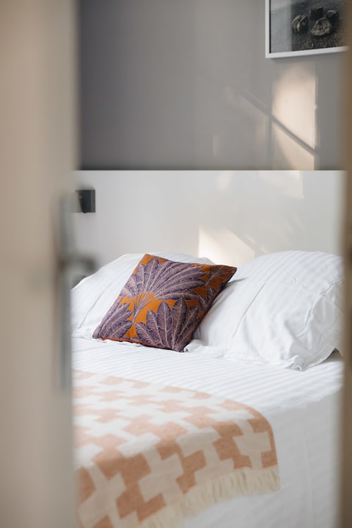 Chambre douillet de La Maison D'olivier avec literie blanche, oreillers décoratifs et lumière naturelle du jardin