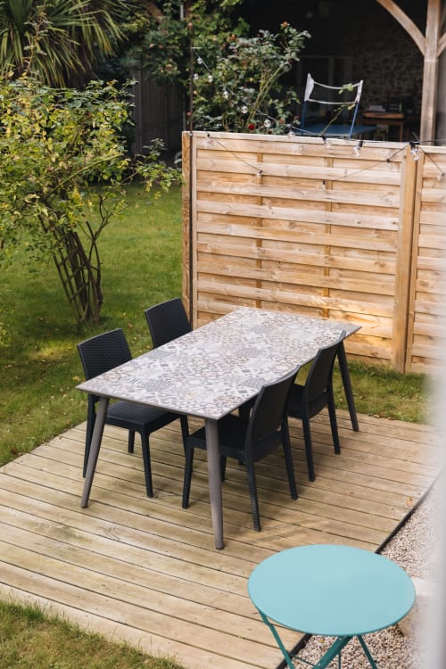 Terrasse du gîte La Maison D'olivier avec table à manger, chaises et petite table turquoise sur une terrasse en bois