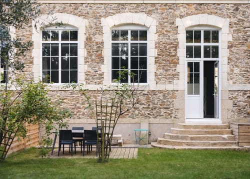 Façade en pierre de La Maison D'olivier avec fenêtres en arc, coins détente au jardin et vue sur la pelouse à Mesnard la Barotière,
