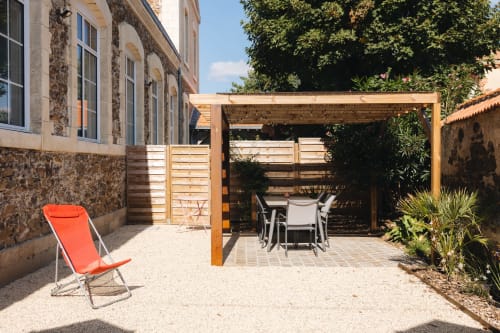 Terrasse du cottage à La Maison D'olivier avec coin repas sous pergola, chaise longue et bâtisse en pierre à Mesnard La Barotière