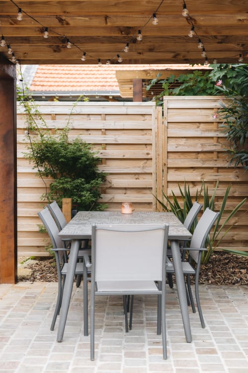 Espace de repas moderne sur la terrasse avec table et chaises sous guirlandes lumineuses à La Maison D'olivier