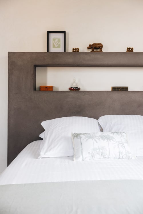 Chambre moderne à La Maison D'olivier avec tête de lit en béton, literie blanche et étagères flottantes décorées