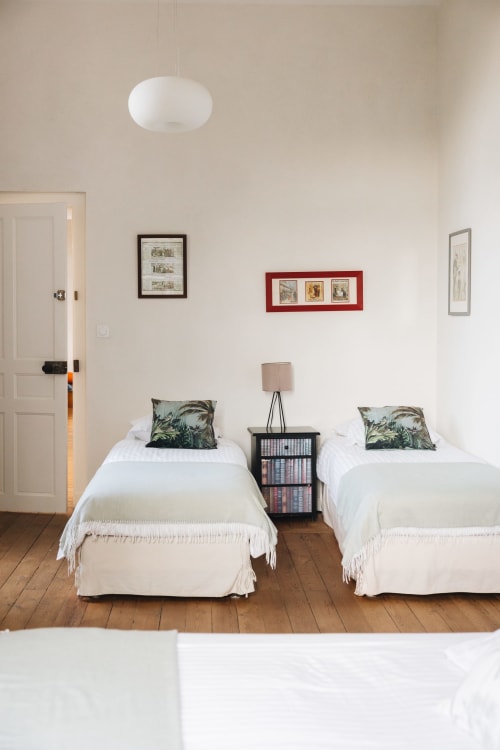 Chambre twin avec literie blanche et coussins tropicaux à La Maison D'olivier, un gîte français à Mesnard La