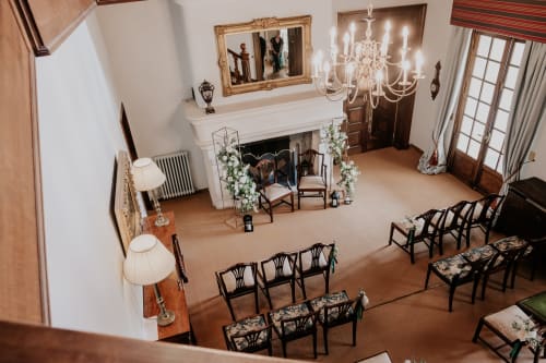 Eleganter Empfangsraum auf dem Domaine de Bize Mirepoix mit Kamin, Kronleuchter und formeller Bestuhlung für eine Veranstaltung