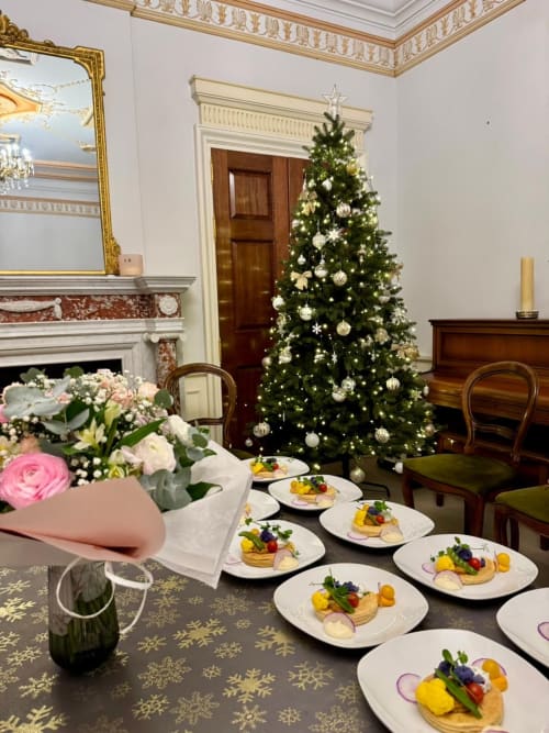 Salle à manger élégante du Domaine de Bize avec amuse-bouches gastronomiques, sapin de Noël, cheminée et centre de table floral.