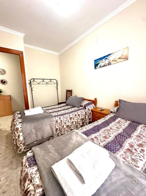 Amplio dormitorio en apartamento de Mérida con dos camas, muebles de madera y paredes color crema