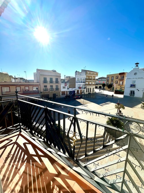 Vista soleada de la plaza desde el apartamento Gestyp-AT en Mérida, España con edificios coloniales y cielo azul despejado