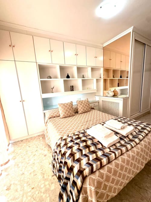 Dormitorio moderno en Mérida con dos camas, ropa de cama con patrones geométricos, armarios blancos empotrados y estantería
