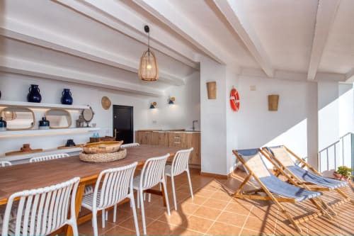 Modern dining and lounge area at Finques Garcia Enrich, Palafrugell, with wooden table, white chairs, beach loungers, and