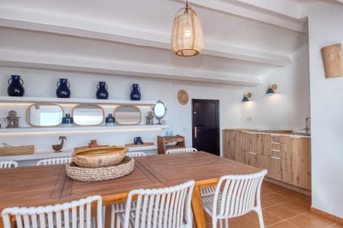 Modern dining area at Finques Garcia Enrich in Palafrugell with wooden table, white chairs, and coastal-style décor shelving.
