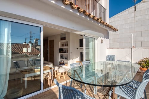 Spacious terrace at Finques Garcia Enrich in Palafrugell with striped chairs, glass table, and sea views