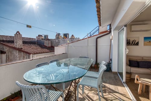 Sunny terrace with dining table at Finques Garcia Enrich hotel in Palafrugell, overlooking historic rooftops