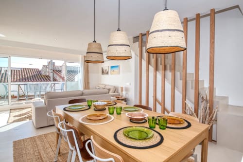 Modern dining area at Finques Garcia Enrich in Palafrugell with wooden table, pendant lights, and coastal views