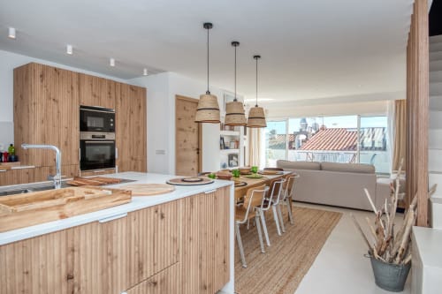 Modern open-plan kitchen and living area at Finques Garcia Enrich, Palafrugell with wood cabinetry, dining table, and city