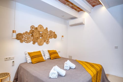 Modern bedroom at Finques Garcia Enrich hotel in Palafrugell with woven basket wall art, golden accents, and comfortable