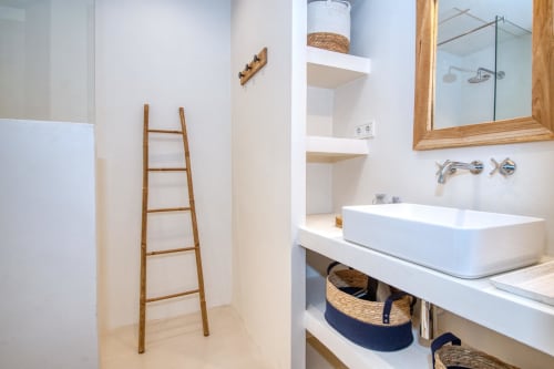 Modern bathroom at Finques Garcia Enrich hotel in Palafrugell with white vessel sink, wooden ladder, and woven storage