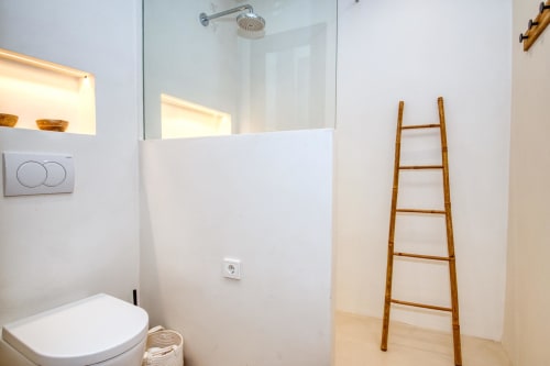 Modern bathroom at Finques Garcia Enrich hotel in Palafrugell with walk-in shower, toilet, and wooden ladder towel rack