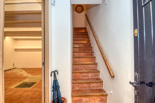 Brick staircase with wooden handrail leading upstairs in Finques Garcia Enrich hotel, Palafrugell, with wood flooring visible