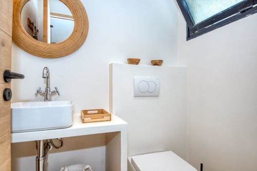 Modern bathroom at Finques Garcia Enrich hotel in Palafrugell with round mirror, white sink, wooden accents and natural