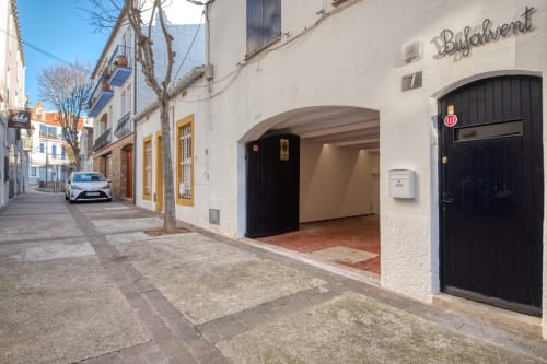 White-walled building entrance in Palafrugell with black doors and arched doorway on charming narrow street