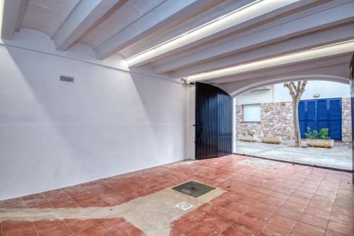 Open carport with terracotta tiles and wooden beams at Finques Garcia Enrich, Palafrugell