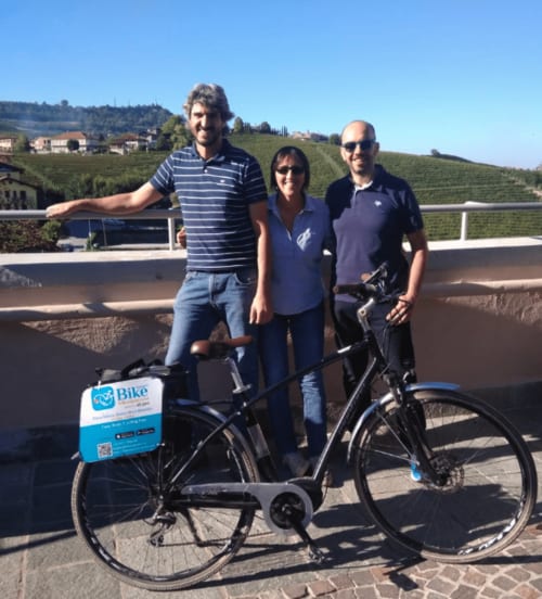 Three people with a blue bike at Agorà Calamandrana hotel overlooking Piedmont vineyards