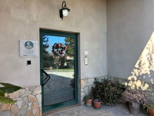 Ingresso con porta verde della Dimora Di Ipno B&B a Vallata, con ghirlanda festiva, piante in vaso e vista del giardino