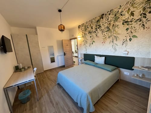 Camera moderna a La Dimora Di Ipno a Vallata con letto matrimoniale, carta da parati con vista giardino, TV e pavimento in legno