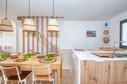 Coastal cottage dining area with wooden table, pendant lights, and modern kitchen in Palafrugell