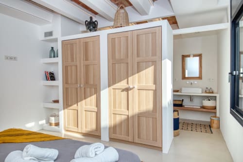 Modern cottage bedroom with wooden wardrobe, white shelving, and ensuite bathroom in Palafrugell seaside property