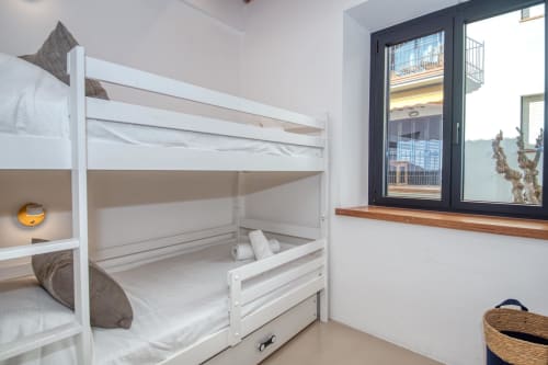 White bunk bed with storage in bright cottage bedroom with sea view windows at Finques Garcia Enrich, Palafrugell
