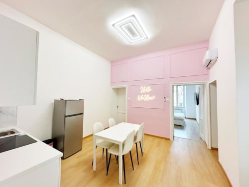 Moderna zona cucina-pranzo rosa e bianca al St Mary Major Loft Roma con insegna al neon e pavimenti in legno
