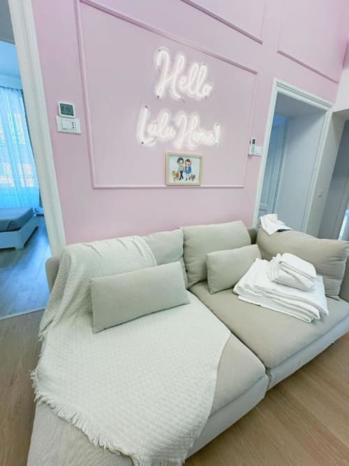 Divano beige con cuscini in camera rosa con insegna neon 'Well Loved' presso St Mary Major Loft, Roma