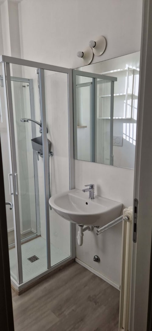 Modern bathroom with glass shower enclosure, white pedestal sink, and mirror at Lamar Suites Seafront Apartments in Misano