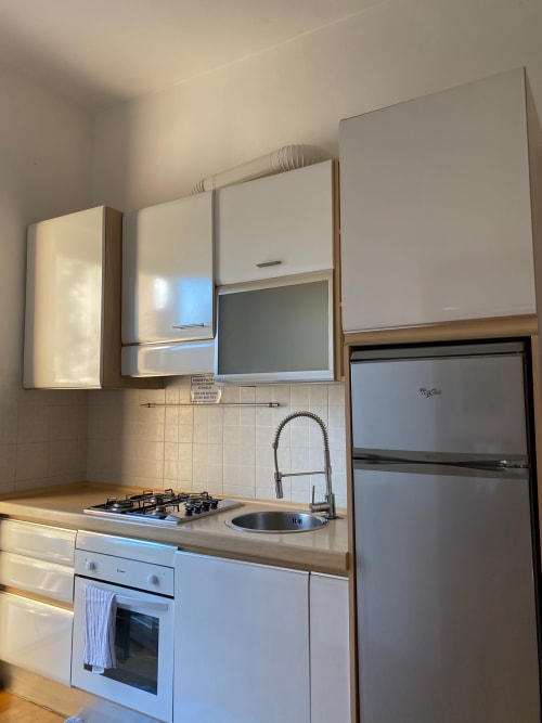 Angolo cottura moderno nell'Apartment Roma 1 di THE V Collection con piano cottura a gas, lavello, forno, frigorifero e mobili bianchi