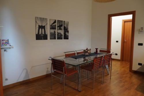 Moderna zona pranzo nell'Appartamento Roma 1 di THE V Collection, Turate con tavolo, sedie rosse e accesso alla cucina