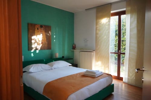 Camera moderna di Roma 1 Apartment, THE V Collection a Turate con parete azzurra, letto matrimoniale, porte finestre con vista giardino